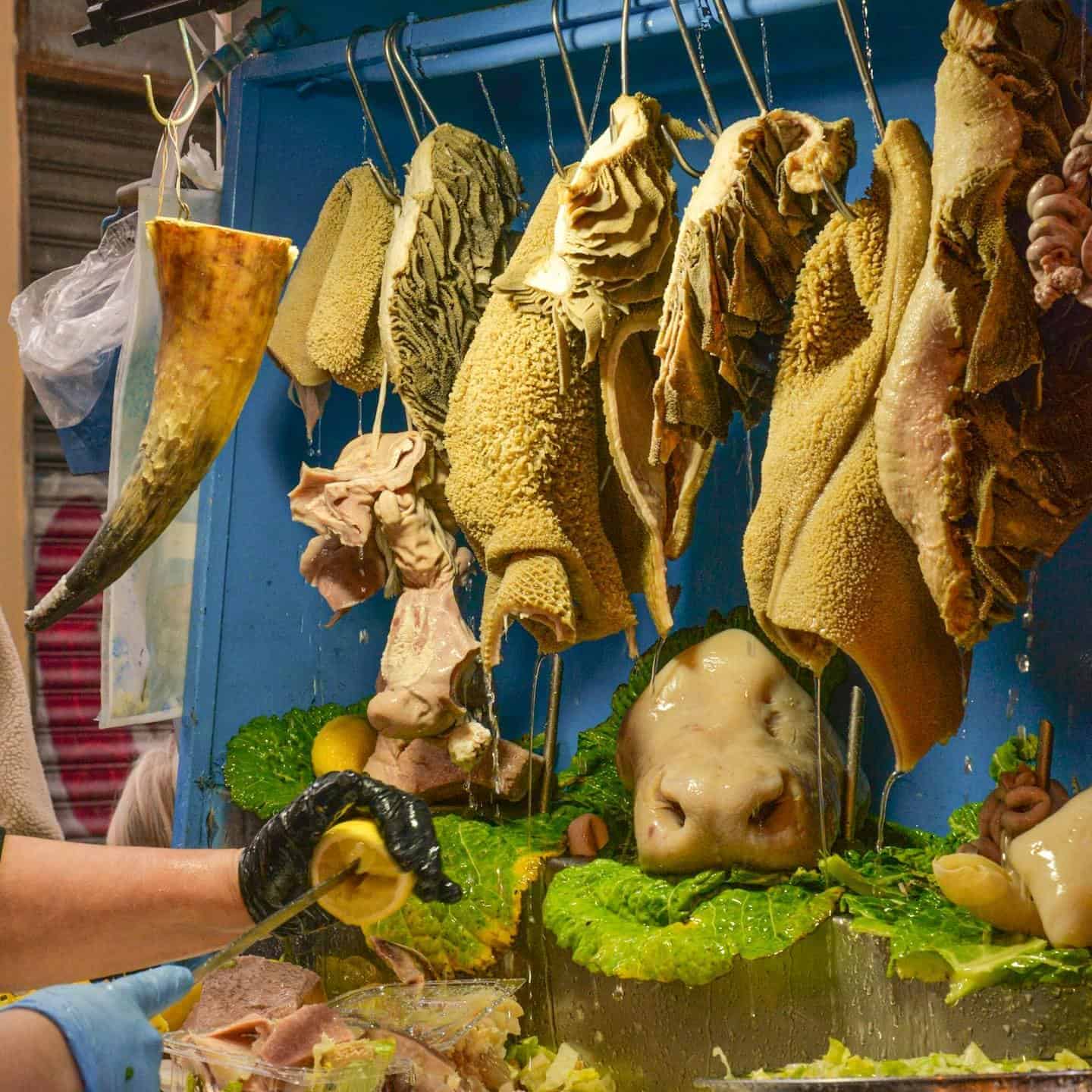 A vibrant display of honeycomb tripe and other offal hanging in an outdoor market stall, showcasing traditional selection.