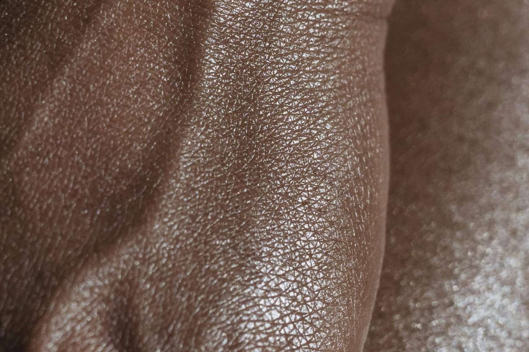 Closeup of crop unrecognizable ethnic person with veins on hand touching glowing body skin