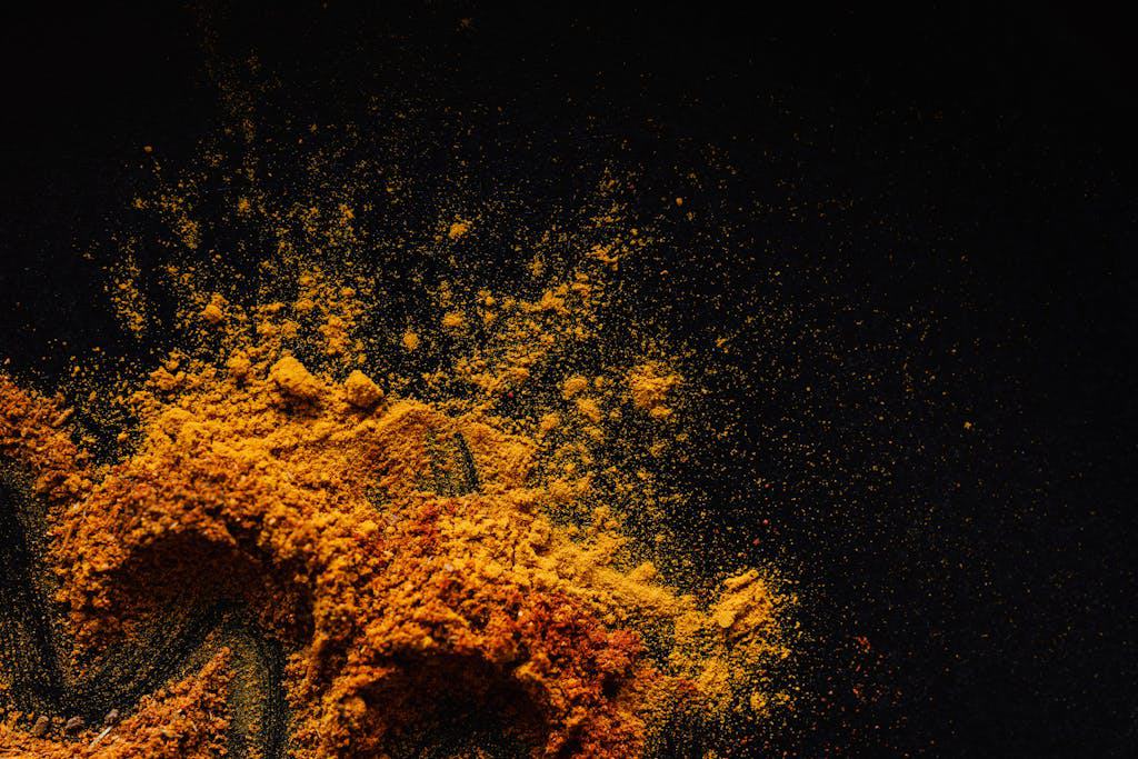 Colorful and aromatic spices spilled on a dark surface, showcasing culinary diversity.