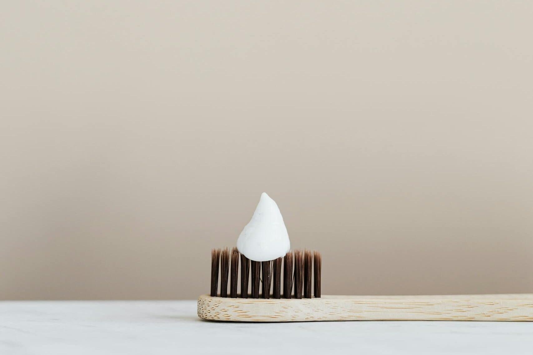 Elegant minimalist photo of a bamboo toothbrush with a dollop of bentonite toothpaste, ideal for hygiene themes.