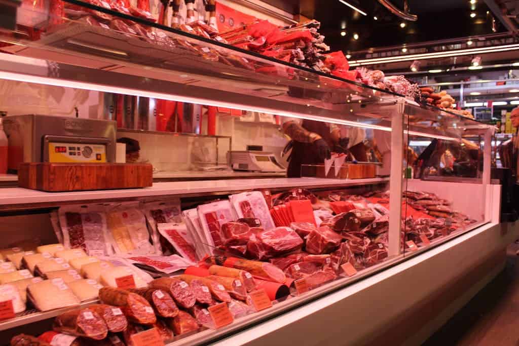 Fresh meat selection in a Barcelona market deli, vibrant display and diverse cuts.