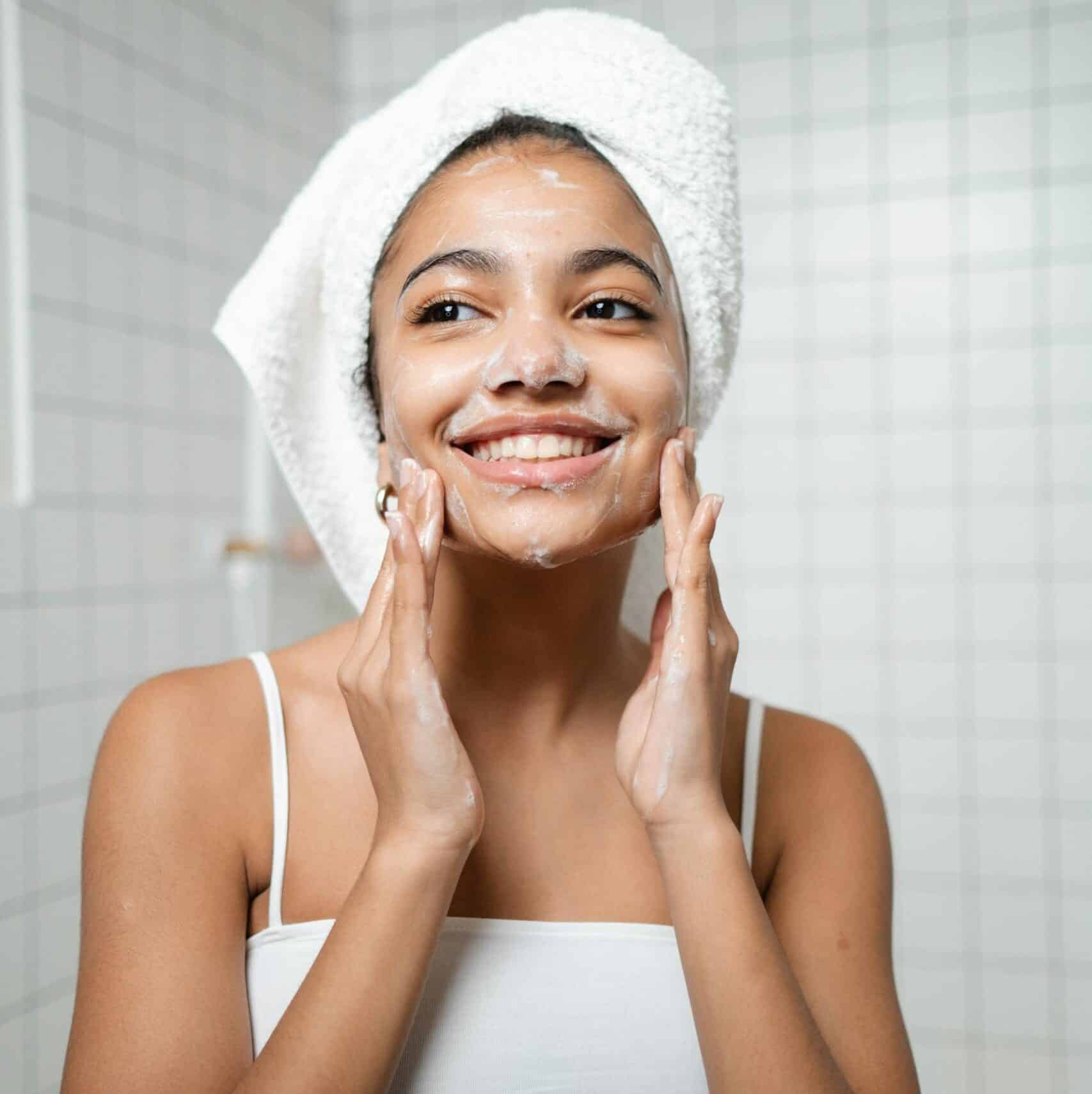 Smiling woman with zeolite wash in a bathroom, embracing self-care and fresh skin.